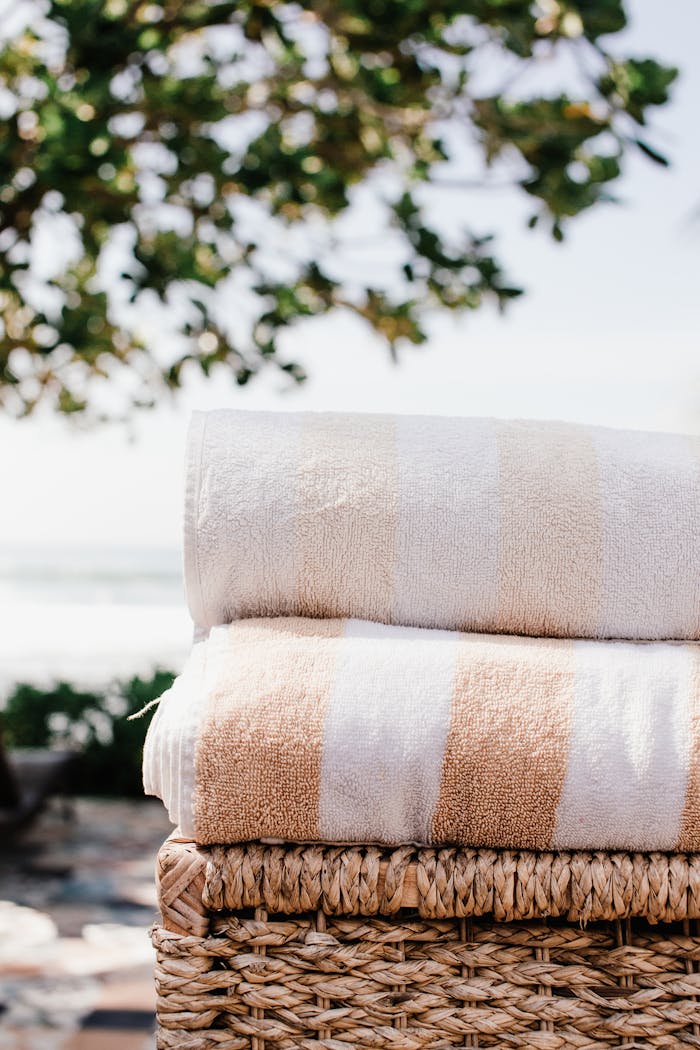 Two stacked bath towels in a wicker basket with outdoor natural background.