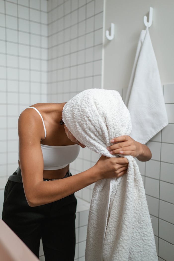 Young woman using a towel to dry her hair after a shower in a contemporary bathroom.